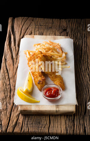 Frisch zubereiteter Fisch und Chips auf einem rustikalen hölzernen Hintergrund. Gastropub Stil essen. Stockfoto