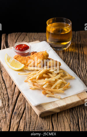 Frisch zubereiteter Fisch und Chips auf einem rustikalen hölzernen Hintergrund. Gastropub Stil essen. Stockfoto