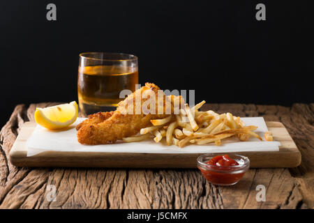 Frisch zubereiteter Fisch und Chips auf einem rustikalen hölzernen Hintergrund. Gastropub Stil essen. Stockfoto