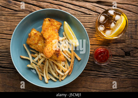 Frisch zubereiteter Fisch und Chips auf einem rustikalen hölzernen Hintergrund. Gastropub Stil essen. Stockfoto