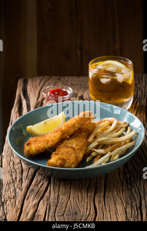 Frisch zubereiteter Fisch und Chips auf einem rustikalen hölzernen Hintergrund. Gastropub Stil essen. Stockfoto
