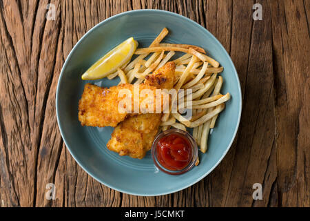 Frisch zubereiteter Fisch und Chips auf einem rustikalen hölzernen Hintergrund. Gastropub Stil essen. Ansicht von oben. Stockfoto