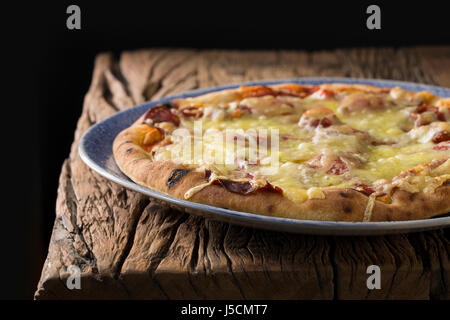 Frischer italienische Pizza serviert auf einem rustikalen Holztisch. Stockfoto