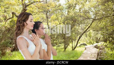 Digital Composite Doppelbelichtung von Frauen mit den Händen umklammert meditieren im Wald Stockfoto