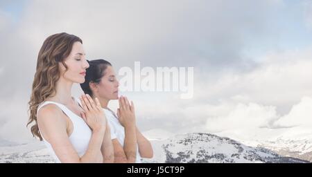 Digital Composite Doppelbelichtung von Frauen mit den Händen umklammert von schneebedeckten Bergen meditieren Stockfoto