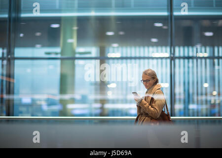 Junge Beifahrerin am Flughafen mit ihrem Tablet-PC während des Wartens auf ihren Flug (getönten Farbbild) Stockfoto