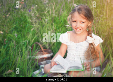 Niedliche kleine Mädchen Buch auf Natur Stockfoto