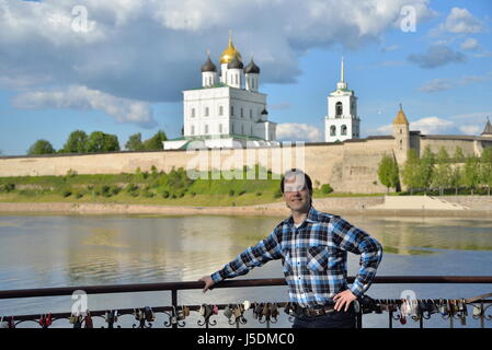 Ein junger Mann steht auf der Aussichtsplattform auf dem Hintergrund der Dreifaltigkeitskathedrale in Pskow Stockfoto