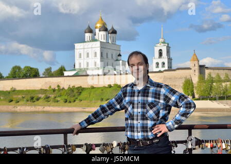 Ein junger Mann steht auf der Aussichtsplattform auf dem Hintergrund der Dreifaltigkeitskathedrale in Pskow Stockfoto