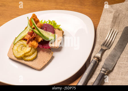 Dänische Spezialitäten und nationale Gerichte, qualitativ hochwertige Open Sandwich, Leber Pastete mit Speck eingelegte Gurken, rote Beete und Gurke, serviert auf einem Teller neu Stockfoto