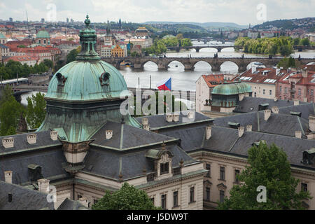 Karlsbrücke und andere Brücken über die Moldau aus dem Garten der Villa Kramář (Kramářova Vila) in Prag, Tschechische Republik abgebildet. Im Vordergrund sieht man die Kuppel der Académie Straka (Strakova Akademie). Die Gebäude des tschechischen Architekten Václav Roštlapil wurde 1891-1896 erbaut und diente nun als Sitz der Regierung der Tschechischen Republik. Stockfoto