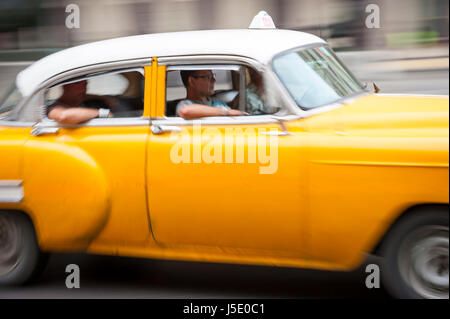 Havanna - Juni 2011: Helle gelbe amerikanische Oldtimer arbeiten als Anteil Taxi nimmt Passagiere entlang der Küstenpromenade Malecón Straße. Stockfoto