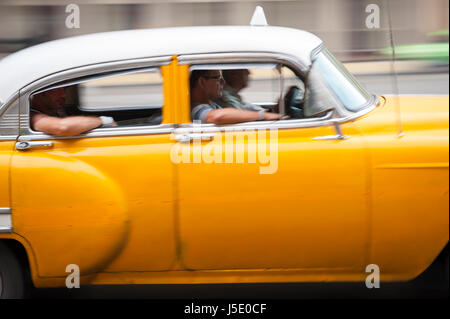 Havanna - Juni 2011: Helle gelbe amerikanische Oldtimer arbeiten als Anteil Taxi nimmt Passagiere entlang der Küstenpromenade Malecón Straße. Stockfoto