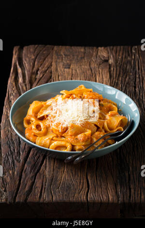 Pasta mit Meeresfrüchten mit Tomatensauce und Parmesan. Auf einem rustikalen Holztisch sitzend. Stockfoto