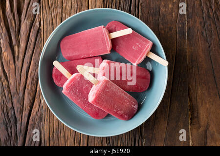 Hausgemachte Himbeeren und Vanilleeis erscheint auf einem rustikalen Holz Hintergrund. Berry Eis Eis am Stiel. Sommer essen. Stockfoto