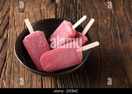 Drei hausgemachte Himbeeren und Vanilleeis erscheint auf einem rustikalen Holz Hintergrund. 3 Berry Eis Eis am Stiel. Sommer essen. Stockfoto