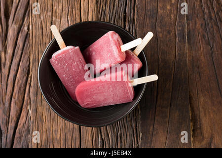 Drei hausgemachte Himbeeren und Vanilleeis erscheint auf einem rustikalen Holz Hintergrund. 3 Berry Eis Eis am Stiel. Sommer essen. Stockfoto