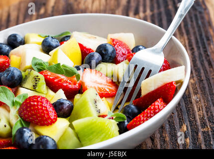 Schale mit Obst-Salat mit Erdbeeren, Blaubeeren, Äpfel, Kiwi, Bananen in Scheiben schneiden, gesunde saisonale Sommer Früchte Salat Sortiment Stockfoto