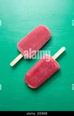 Zwei hausgemachte Himbeeren und Vanilleeis öffnet auf grünem Holz Hintergrund. 2 Himbeer Eis Eis am Stiel. Sommer essen. Stockfoto