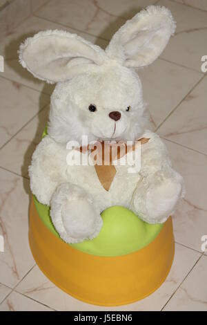 Weiße Teddy Hase Spielzeug sitzt auf einer Kinder-Toilette Stockfoto