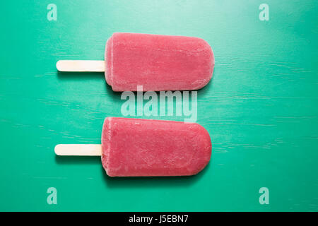 Zwei hausgemachte Himbeeren und Vanilleeis öffnet auf grünem Holz Hintergrund. 2 Himbeer Eis Eis am Stiel. Sommer essen. Stockfoto