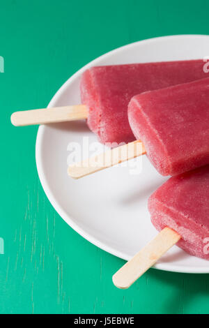 3 hausgemachte Himbeeren und Vanilleeis öffnet auf grünem Holz Hintergrund. Berry Eis Eis am Stiel. Sommer essen. Stockfoto