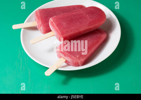 3 hausgemachte Himbeeren und Vanilleeis öffnet auf grünem Holz Hintergrund. Berry Eis Eis am Stiel. Sommer essen. Stockfoto