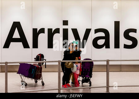 Eine Familie nehmen ein Selbstporträt In der Ankunftshalle des Flughafens Heathrow, London, UK Stockfoto