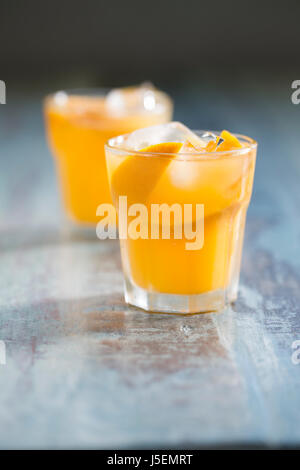 Frisch gepresster Orangensaft auf einem rustikalen Holztisch sitzend. Stockfoto