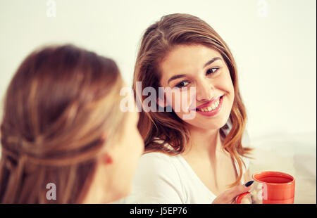 glückliche junge Frauen trinken Tee mit Süßigkeiten zu Hause Stockfoto