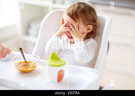 Baby im Hochstuhl sitzen und Essen zu Hause Stockfoto