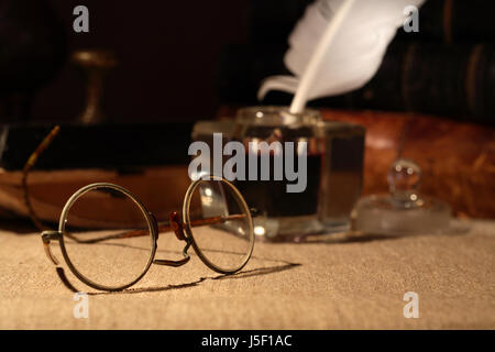 Vintage Stillleben. Alte Brille Closeup auf dunklem Hintergrund mit Tintenfaß und Bücher Stockfoto