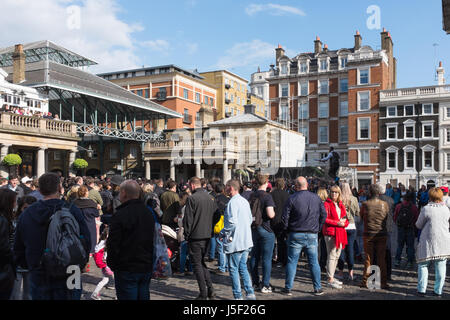 Touristen, die gerade einer Straße Entertainer in Covent Garden Market in London Stockfoto