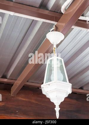 Weißmetall-Lampe mit der elektrischen Glühbirne auf der Metallstange des modernen Hauses. Stockfoto