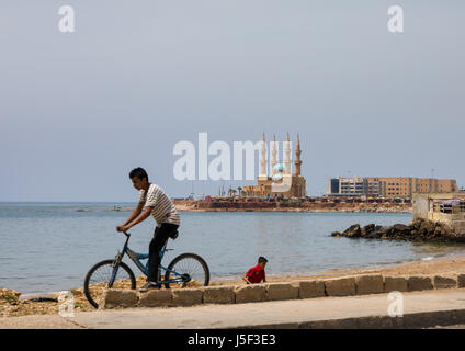 Kind auf dem Fahrrad vor Corniche el Mina Moschee, North Governorate, Tripoli, Libanon Stockfoto