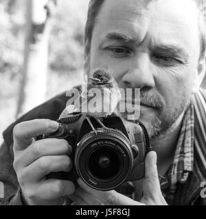 Ein Fotograf mit einer jungen Songbird auf seiner Kamera Stockfoto