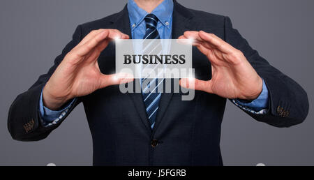 Geschäftsmann hält weiße Karte mit Business anmelden, grau - Stock Photo Stockfoto
