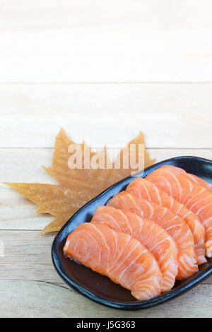 In Scheiben geschnittenen rohen Lachs auf schwarzen Druckplatte mit Holz Hintergrund Stockfoto