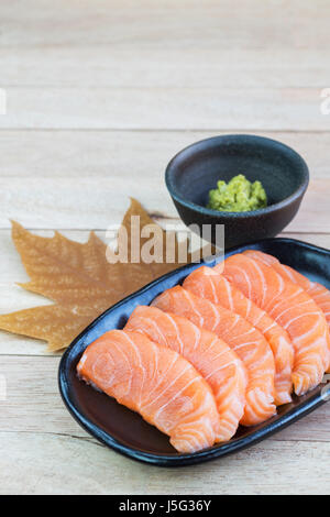 In Scheiben geschnittenen rohen Lachs auf schwarzen Druckplatte mit Holz Hintergrund Stockfoto