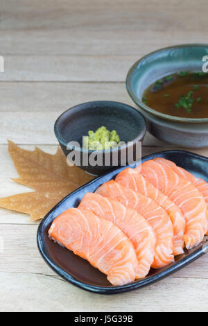 In Scheiben geschnittenen rohen Lachs auf schwarzen Druckplatte mit Holz Hintergrund Stockfoto