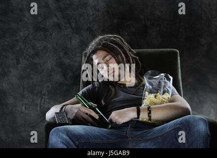 Ein Mann schläft auf der Couch mit Bier und chips Stockfoto