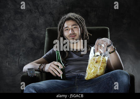 Junger Mann vor dem Fernseher Kartoffelchips Essen und trinken Bier Stockfoto