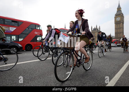 Weibliche Tweed Run-Radfahrerin in London überquert die Westminster Bridge, vorbei an den Houses of Parliament Stockfoto