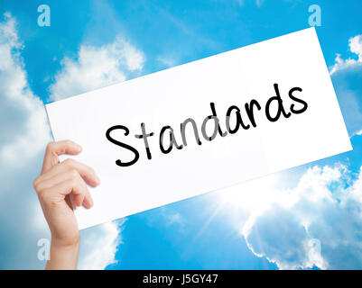 Normen-Zeichen auf weißem Papier. Mann Hand Holding Papier mit dem Text. Auf Himmelshintergrund isoliert.   Business-Konzept. Stock Foto Stockfoto
