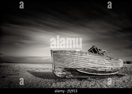 Einzelne aufgegeben altes Fischerboot auf einem Kiesstrand in Monochrom. Dungeness, England Stockfoto