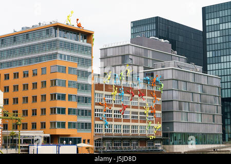 Düsseldorf, Deutschland - 14. April 2017: Bunte Figuren auf Roggendorfer Haus bauen. Moderne Bürogebäude im Medienhafen Stockfoto