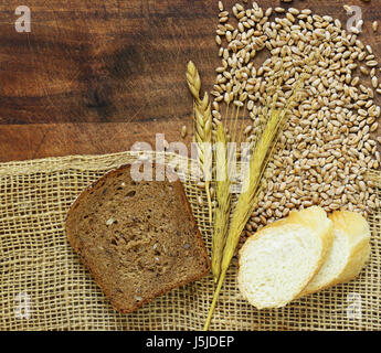 Hölzerne Hintergrund mit groben Stoff Sackleinen und Weizen Ohren und Körner Stockfoto