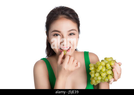 Junge schöne asiatische Frau essen frische Weintrauben isoliert auf weißem Hintergrund Stockfoto