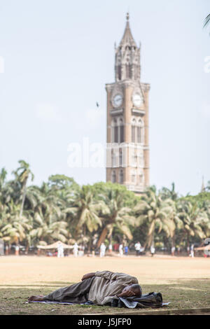 Ein Mann schläft in einer Grille Spielen Gelände mitten am Tag in Mumbai, Indien Stockfoto