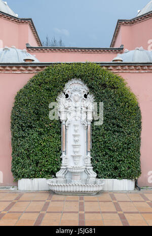 Weiße Marmor gemeißelt Wandbrunnen umgeben von grünen Blättern über rosa Steinmauer und orange Keramikboden im Sultan Ahmed (Sultanahmet) man gefliest Stockfoto